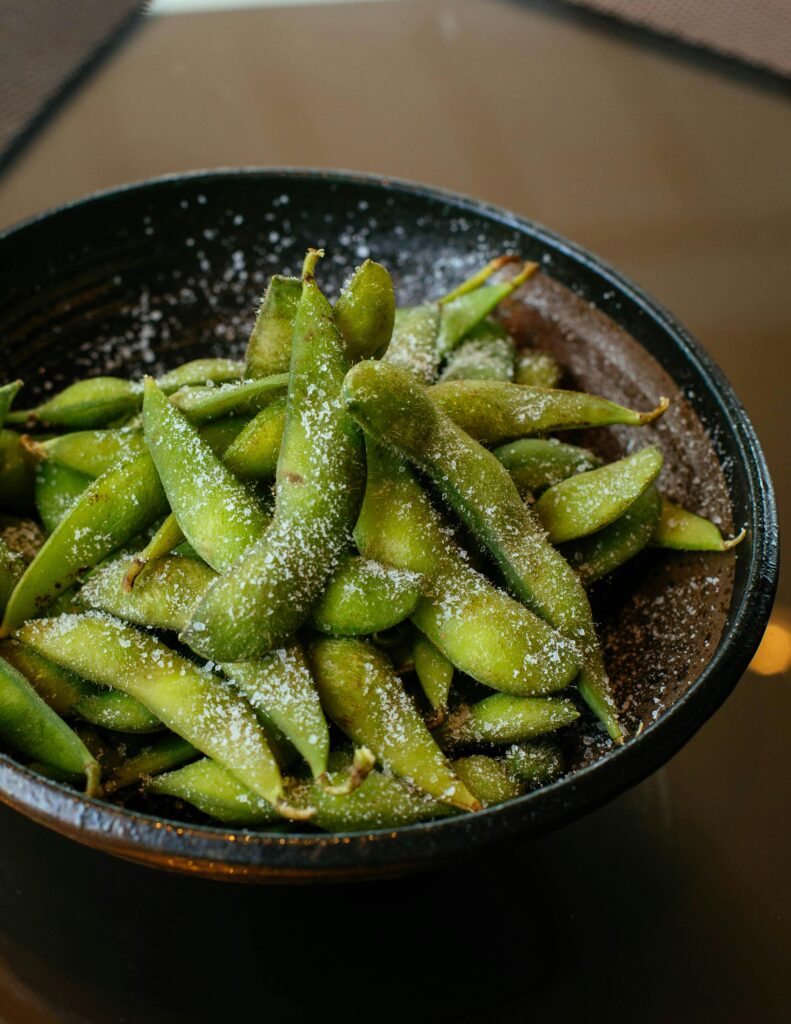 Close-up of fresh salted edamame pods in a black bowl, perfect for appetizer or snack.