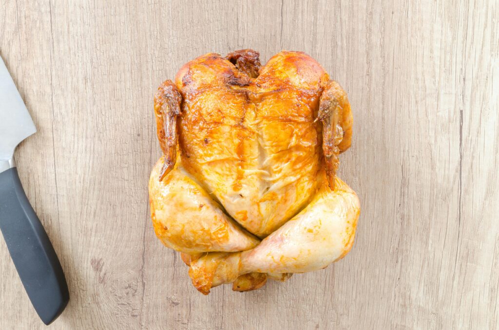 A crispy whole roasted chicken on a wooden board, perfect for a delicious dinner.